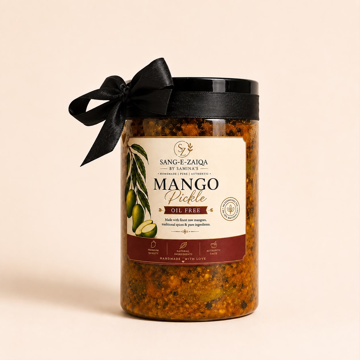 A glass jar of Sang-E-Zaiqa Mango Pickle by Samina, featuring a black lid with a black ribbon bow, a cream-colored label with green mango and olive illustrations, and visible orange-red pickle contents. The jar is set against a solid, warm beige background.